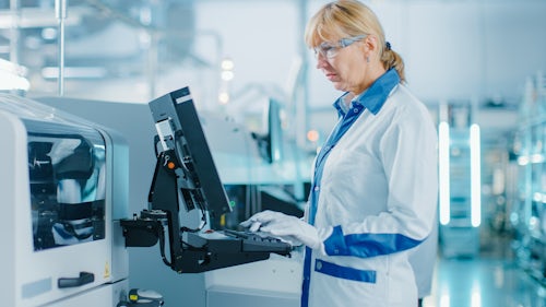 Frau in einer pharmazeutischen Produktionsstätte, die an einem Computer arbeitet.
